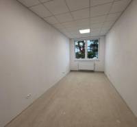 A white room with a window, radiator, and a floor with a wooden decor in the offices.