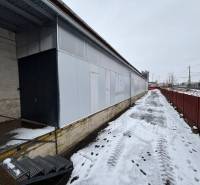 A snow-covered area with offices in Poprad, next to the tracks and a metal fence.