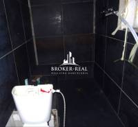 A bathroom with dark tiles and a toilet in a family house.