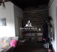 Interior of a family house with a sofa and a coat rack, panelled wall in the background.