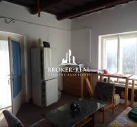 A room in a family house with a lit table by the window, an armchair, and a dining table.