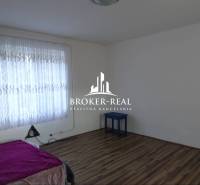 A room with a bed, curtains, and a wooden decor floor in a family house.