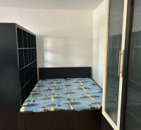 Bedroom in a studio apartment with a bed and storage cabinets.