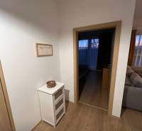 Interior of a 2-room apartment with a wooden decor floor, light furniture and decorations.