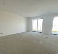 A spacious room in a family house with a concrete floor and large windows.