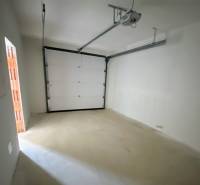 A garage with white walls and an electric gate in a family house.
