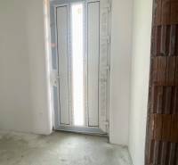 Entrance door in the interior of a family house with a concrete floor and an unplastered brick wall.