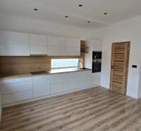 A kitchen with white cabinets and wooden decor in a family house, floor with wooden decor.