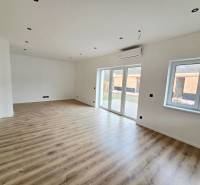 The interior of a family house with a wooden decor floor and large windows.