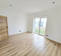 Interior of a family house with a wooden decor floor and a large window to the garden.