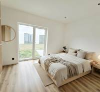 Bright bedroom with wood-patterned flooring and a large window in a family house.