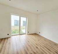 Interior of a family house with white walls, wood-patterned flooring, and a large window.