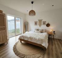 Bedroom with a bed, round carpet, wardrobe, and wooden decor flooring in a family house.