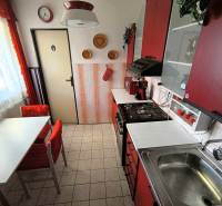 A kitchen in a family house with red cabinets, a dining table, and tiles.