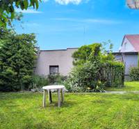 The garden of a family house in Nováky with a lawn, a table, and ornamental shrubs.