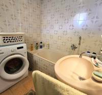 Bathroom in a family house with a bathtub, washing machine, and sink.