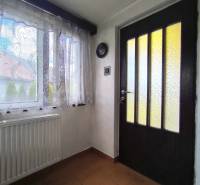 Interior of a family house with a window, radiator, and wooden door with glass inserts.