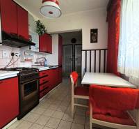 A kitchen in a family house. Red cabinets, dining table, curtains, coffee maker.