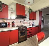Red kitchen in a family house with a microwave and a stove.