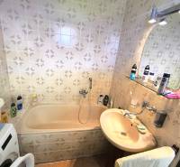 Bathroom with a bathtub and a washing machine in a family house with tiles.