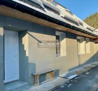 A family house in Hronec with snow on the roof, white doors, and a wooden bench.