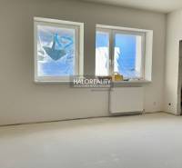 A room in a family house with windows and a radiator, unused space ready for completion.