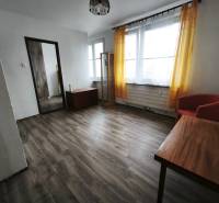 Living room in a studio apartment with a wood-patterned floor and yellow curtains.