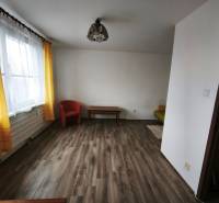 Living room in a studio apartment with wood-patterned flooring and yellow curtains.