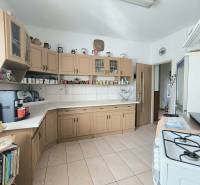 A kitchen in a family house with wooden cabinets and ceramic tiles.
