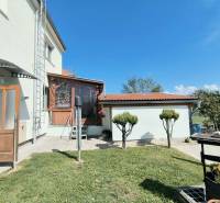 The exterior of a family house in Partizánske with a veranda and a garden under a blue sky.