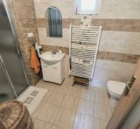Bathroom with toilet in a family house with a shower, tiles, and a storage basket.