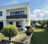 A family house in Partizánske surrounded by a garden with trees and a green lawn.
