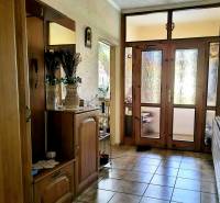A hallway in a family house with a mirror, decorations, and glass doors.