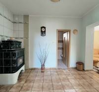 Interior of a family house with green tiles, a tiled stove, and paving.
