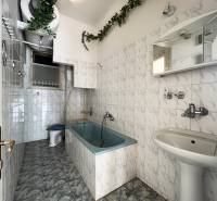 A bathroom with a bathtub, white tiles, and green decoration in a 5 or more room apartment.