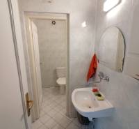 Bathroom in offices with a mirror, sink, and toilet on white tiles.