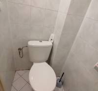 A restroom in an office with white tiles and flooring.