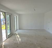 A spacious room in a family house with large windows and a concrete floor.
