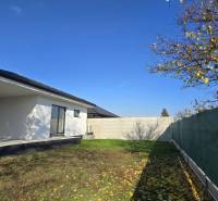 A family house in Piešťany with a garden, fencing, and a blue sky.