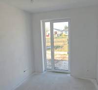 A white room in a family house with a large window and a view of the garden.