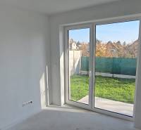 Interior of a family house with a large window to the garden, white walls and floor.