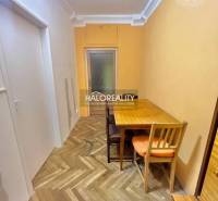A narrow corridor with a table and chairs, a floor with a wooden decor in a 4-room apartment.