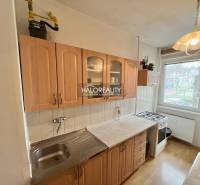 A kitchen in a 4-room apartment with wooden decor cabinets and a gas stove.