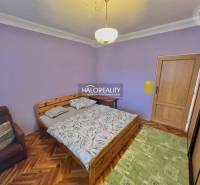 A bedroom in a 4-room apartment with a wooden decor floor and purple walls.