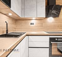 A kitchen in a 2-room apartment with a countertop and wall with a wood decor.
