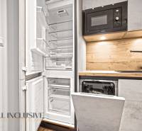 A kitchen in a 2-room apartment with an open refrigerator and a built-in dishwasher.