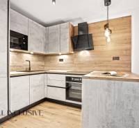 A kitchen in a 2-room apartment with a wood-decor floor and wood paneling.