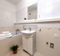 A bathroom with a bathtub and a sink in a 2-room apartment with decorative tiles.
