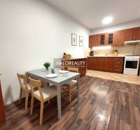 A kitchen in a 2-room apartment with a wooden decor floor and a dining table.