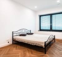 A bedroom in a family house with a metal bed, white walls, and a wooden decor floor.